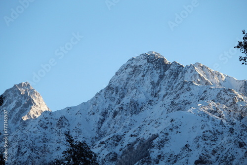 Two majestic Himalayan peaks,their highest cliffs kiss the dawn's embrace.As the sun's golden embrace spills across the horizon,its gentle rays caress the snow-covered cliffs, creating incredible view