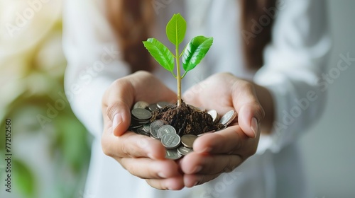 Businesswoman's Hand Holding Tree with Growing Plant on Coins - Concept of Saving Money and Earth Day