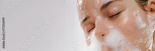 Banner portrait of a white woman with clear skin washing her face with soap