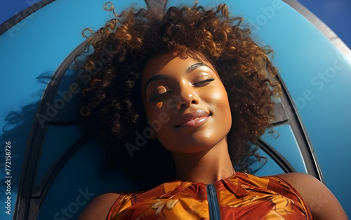 Young African American woman with afro hair is lying and relaxing on sup serfing board with sunshine in the blue sea