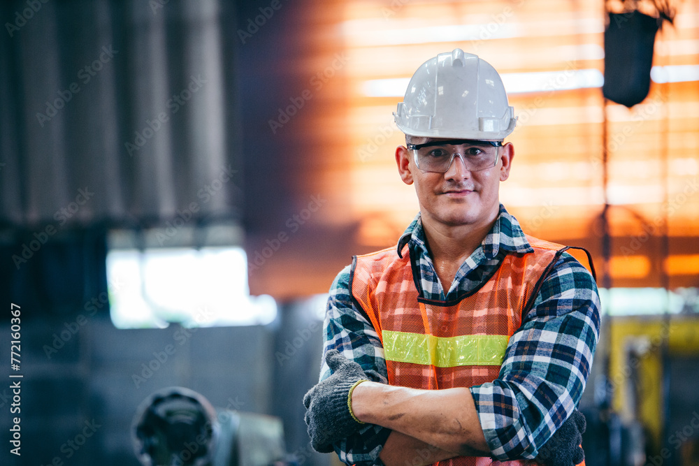 Portrait of male foreman factory wearing hardhat in arms crossed looking at camera standing at the industry factory. Construction worker or builder career in positive attitude. copy space Portrait of male foreman factory wearing hardhat in arms crossed looking at camera standing at the industry factory. Construction worker or builder career in positive attitude. copy space