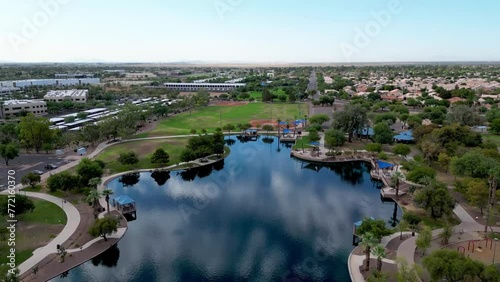 Drone of small lake surrounded by greenery with highway and buildings in Desert Breeze Park photo