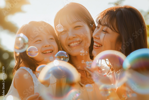 A joyful family moment with a mother and her daughters playing with bubbles in a sunny park. photo