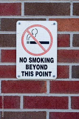 Faded and cracked no smoking sign on a brick wall