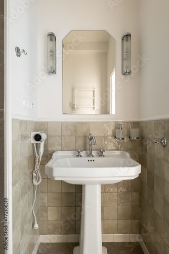 Bathroom with pedestal sink, mirror, and hair dryer