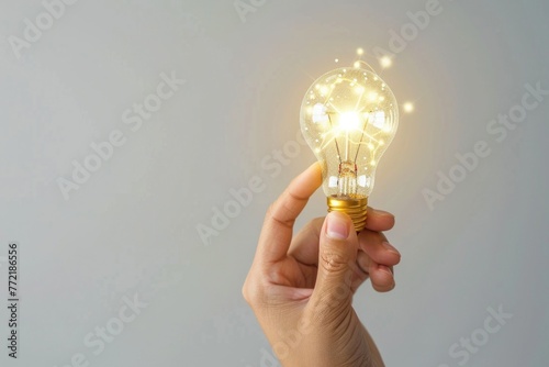 A hand holding a light bulb. The light bulb is glowing and shining brightly. Concept of innovation and creativity