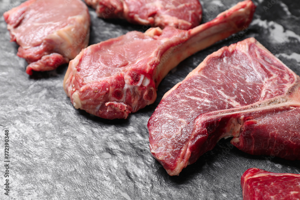 Fresh raw beef cuts on grey textured table, closeup