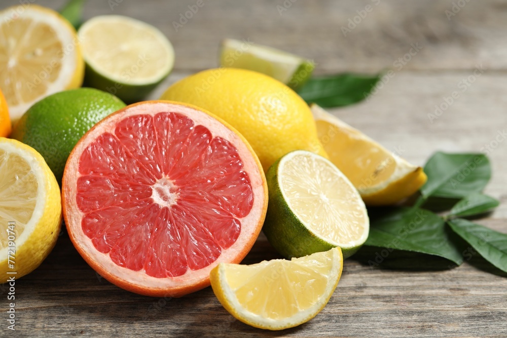 Different fresh citrus fruits and leaves on wooden table, closeup Different fresh citrus fruits and leaves on wooden table, closeup