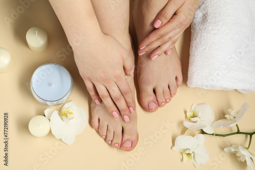 Closeup of woman with neat toenails after pedicure procedure on beige background, top view