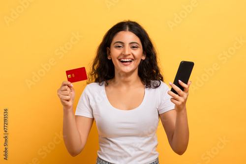 Cheerful woman holding phone and credit card