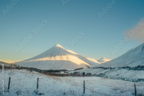 Beinn Dorain, a conical mountain, covered in snow under a blue sky, along the West Highland Way in Scotland photo