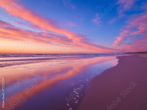 Seascape during sunrise. Bright clouds on the sky. Lines of sand on the seashore. Bright sky during sunset. A sandy beach at low tide. Wallpaper and background.