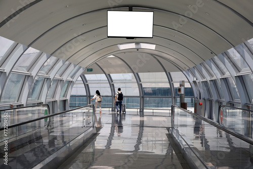 Fototapeta Naklejka Na Ścianę i Meble -  blank white billboard, blank monitor screen inside a station or terminal with people in the background with suitcases or walking in the airport hall