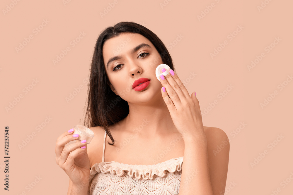 Beautiful young woman with sponge and powder on beige background Beautiful young woman with sponge and powder on beige background