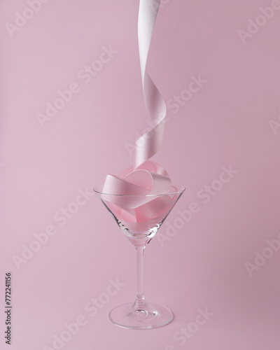 Martini glass with pink party ribbon. Minimal celebration concept.