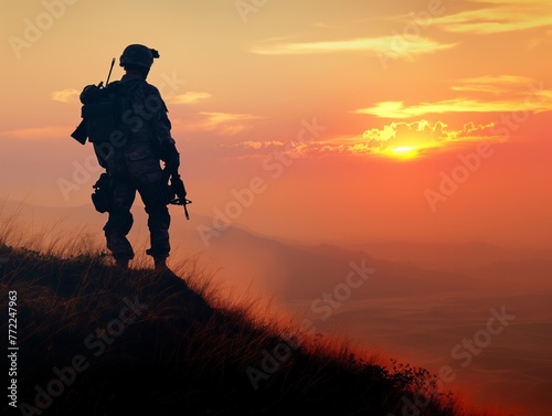 A soldier stands on a hill overlooking a valley with a sunset in the background. Concept of solitude and contemplation, as the soldier is alone in the vast landscape © MaxK