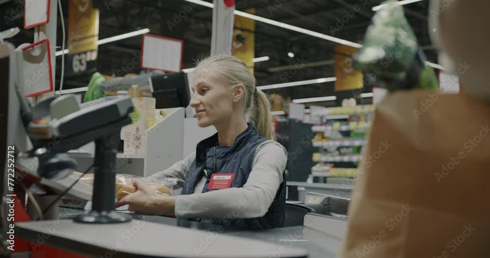 Female cashier scanning food products and giving to customer packing in ...