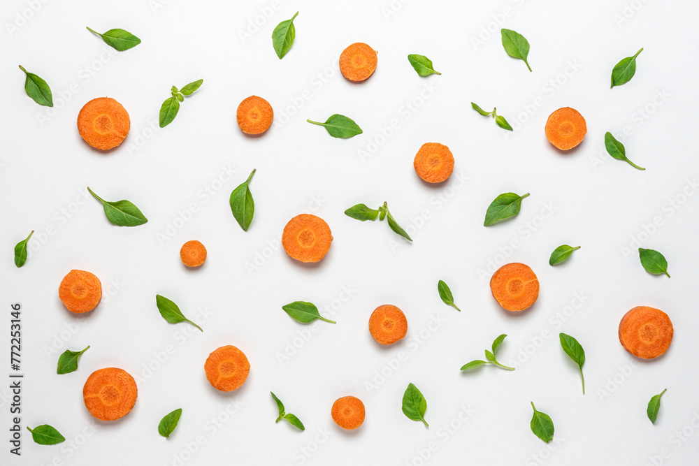 Colorful pattern made of sliced carrots and basil green leaves. Minimal food concept. Colorful pattern made of sliced carrots and basil green leaves. Minimal food concept.