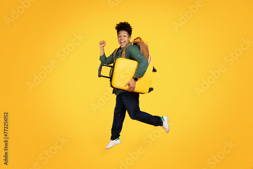 Joyful african american man running with luggage