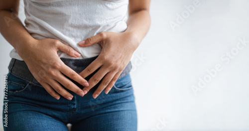 woman grips lower stomach, indicating discomfort, likely from premenstrual syndrome. suffer from PMS premenstrual. White background, copy space photo