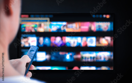 Multimedia streaming concept. Hand holding remote control. TV screen with lot of pictures. Television streaming. VoD content provider. Video service with internet streaming multimedia shows, series.
