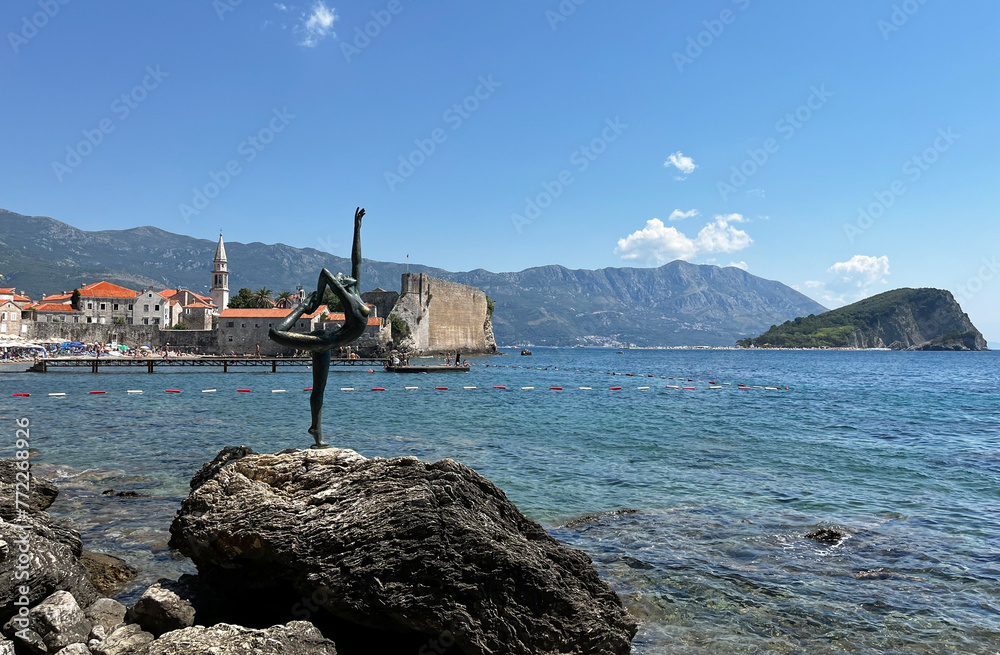 Statue of a ballerina against the backdrop of the old town in Budva. Landmark in the city of Budva, Montenegro