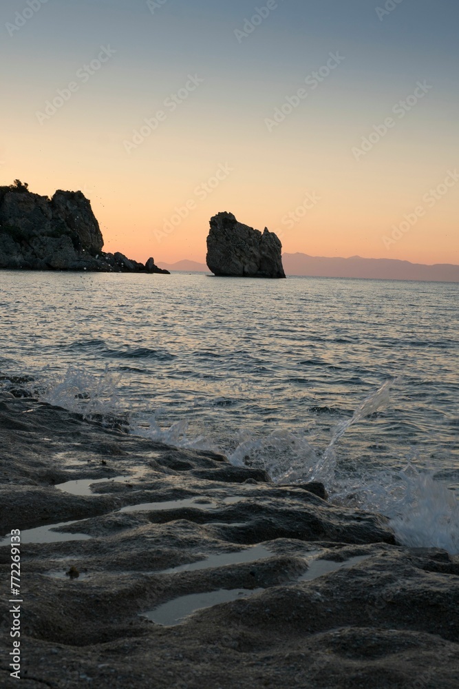 Sandy beach shoreline with an array of stones scattered along the coastline, Greece
