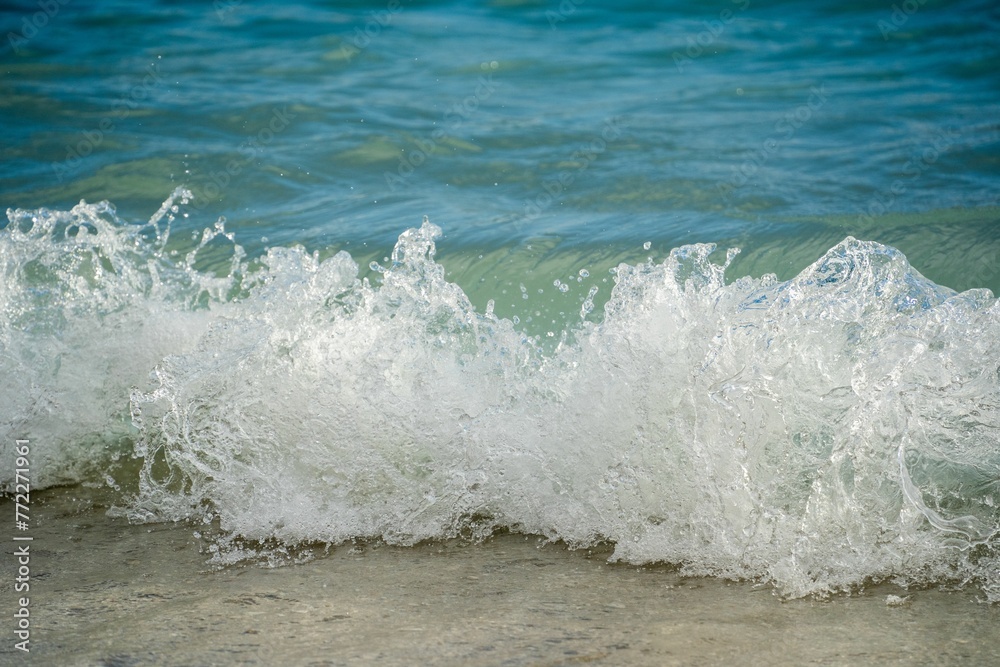 Fototapeta premium Ocean waves crashing against a sandy shore.