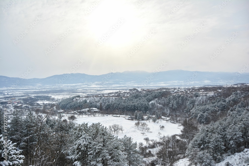 Aerial view of a snow-covered countryside and snow-capped mountains in the wintertime Aerial view of a snow-covered countryside and snow-capped mountains in the wintertime