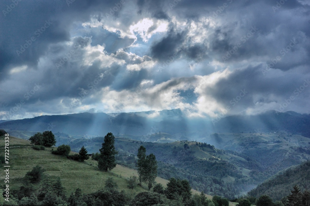 Carpathian Mountains illuminated by a sunbeam shining through a stormy sky in the background