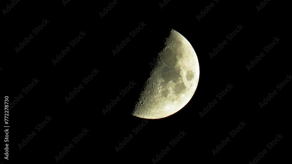 Moon during the First Quarter phase isolated in the dark sky. Moon during the First Quarter phase isolated in the dark sky.