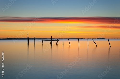 Tranquil scene of a large body of water illuminated by the golden hues of the setting sun