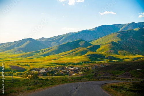 Scenic landscape featuring a rural road leading into a lush valley surrounded by majestic mountains