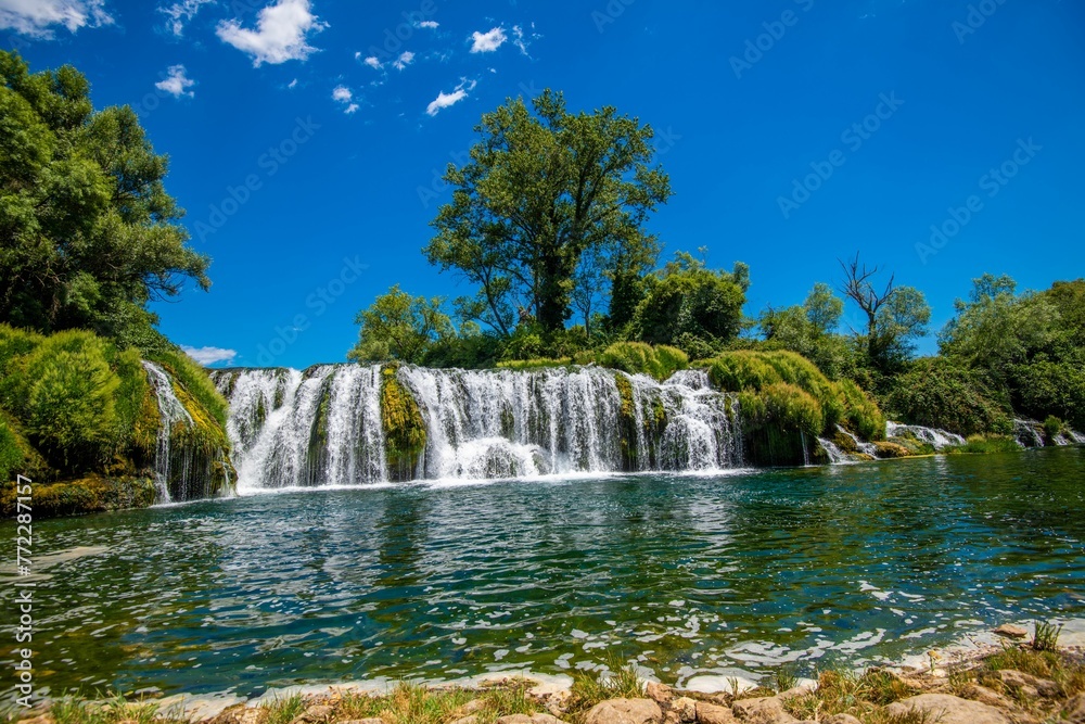 Fototapeta premium Majestic Kravica Waterfall cascading down amidst lush greenery and trees in Bosnia and Herzegovina