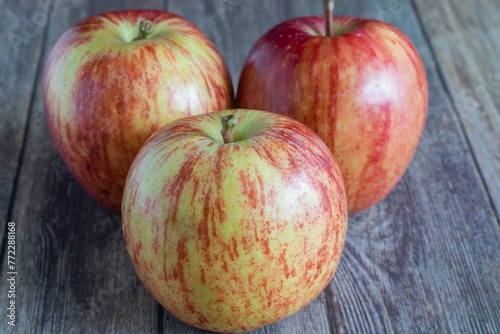 Bright red apples resting on a light wooden surface