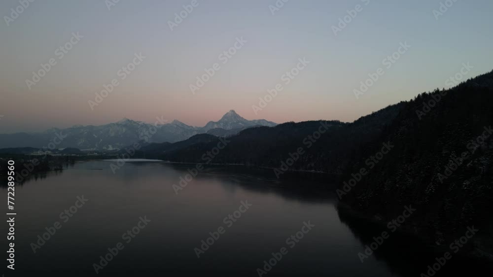 Aerial scene of the silhouette mountains around lake with sunset in Weissensee, Germany