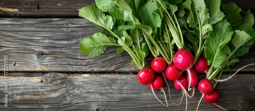A bunch of radishes with vibrant green leaves resting on a wooden table, ready for culinary use.