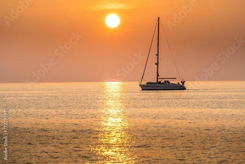 Sailboat silhouetted against a beautiful sunset over the water.