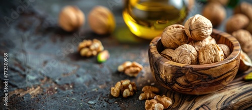 A wooden bowl filled with assorted nuts sits next to a bottle of oil on a table. photo