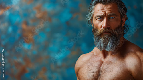 Portrait of a mature bearded man with a thoughtful expression against a textured blue background. photo