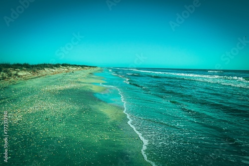 Stunning aerial view of a beach in summertime, with a bright blue ocean