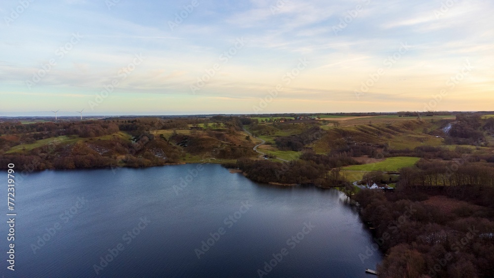 Scenic view of a tranquil lake surrounded by lush greenery at sunset.