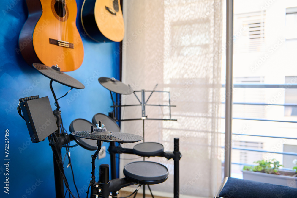 Modern interior of a music studio for home use. Acoustic and electric guitars hanging on blue