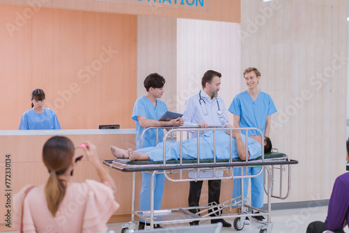 Doctors and nurses are waiting to transfer a patient lying on a bed for treatment, with relatives closely watching over him.