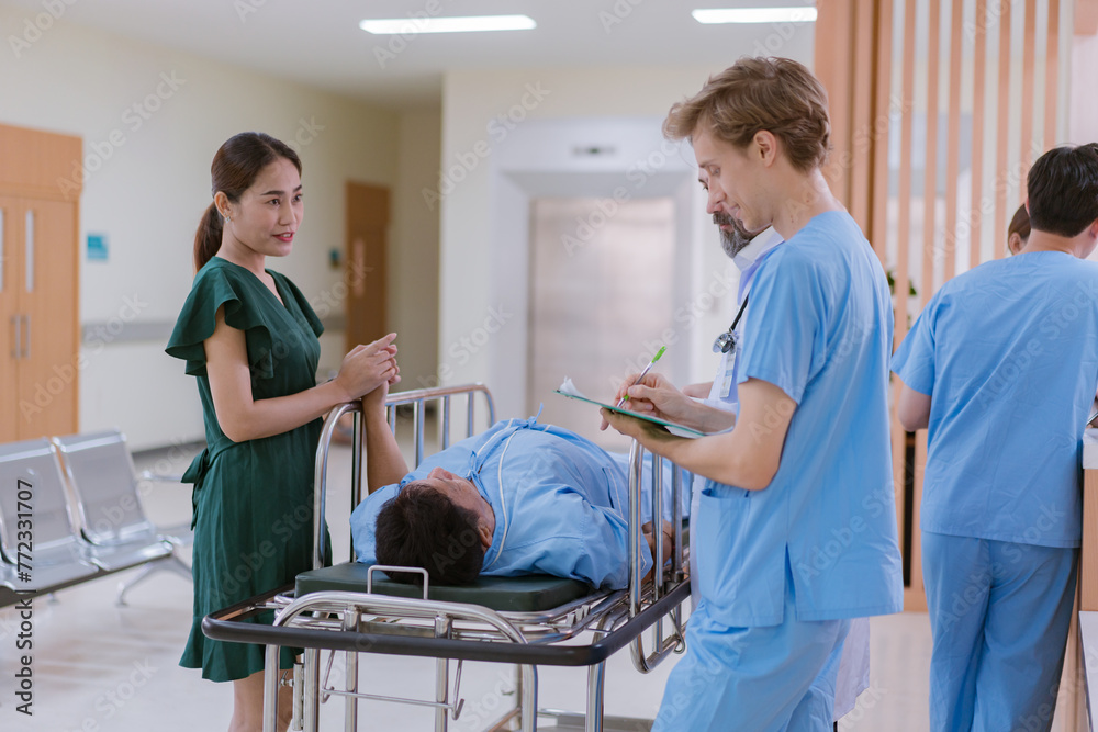 Fototapeta premium Doctors and nurses are waiting to transfer a patient lying on a bed for treatment, with relatives closely watching over him.
