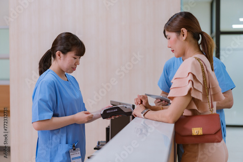 Woman is paying on the reception desk in beauty treatment clinic using contactless credit card.