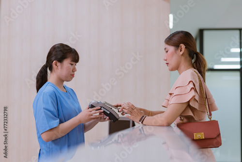Woman is paying on reception desk in beauty treatment clinic using mobile phone