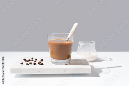 Café con leche en un vaso transparente sobre mármol sobre fondo gris	