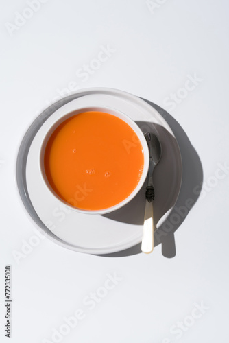 Sopa de zanahoria en un plato sobre fondo gris y blanco. Vista superior