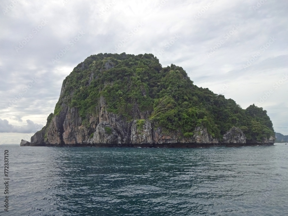 The serene blue sea is complemented by a majestic mountain towering above it, PHI PHI ISLAND, THAILAND The serene blue sea is complemented by a majestic mountain towering above it, PHI PHI ISLAND, THAILAND